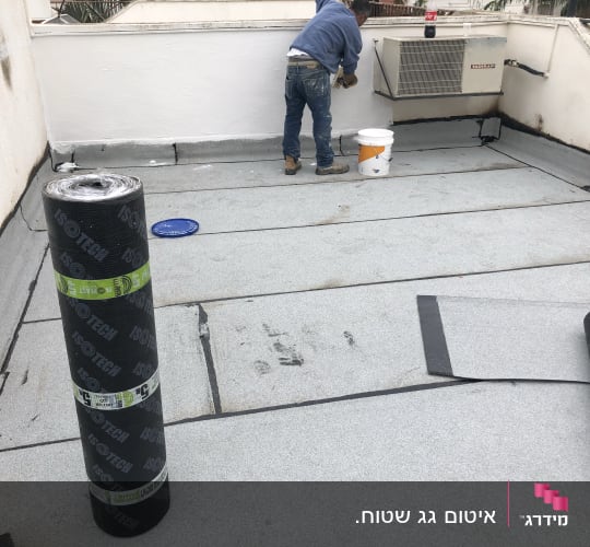 אדם עובד על איטום גג עם יריעות ביטומניות